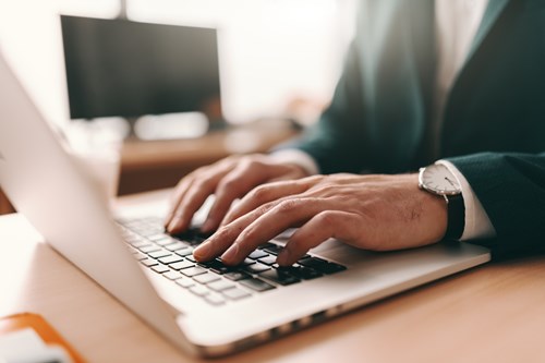 Close up of man typing e-mail on laptop.