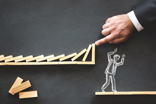 Chalk board illustration of a man at risk of being squashed by wooden dominos