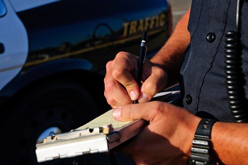 Enforcement officer issues a parking ticket by a car