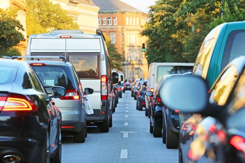 Two rows of traffic on a city center street with trees on either side