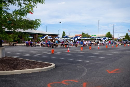 Dining tables and parasols erected in a restaurant parking lot.