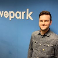 Man in a denim shirt stands in front of a blue wall