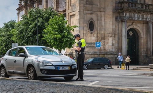 Enforcement officer places a ticket on a silver car parked on-street