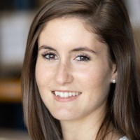 Face of a smiling woman with dark brown hair and brown eyes