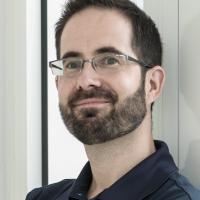 Man with beard and black rimmed glasses wearing a black shirt