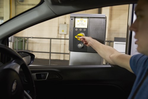 Man in car takes a ticket from a parking barrier machine