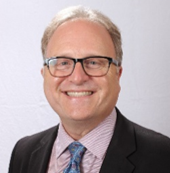 Headshot of a Steve Resnik wearing glasses a pink shirt and blue tie