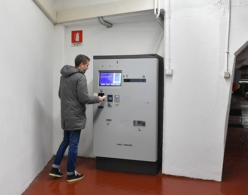 Young man inserting parking ticket into the pay station