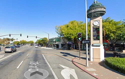 Traffic light junction with a clocktower to the right displaying parking availability