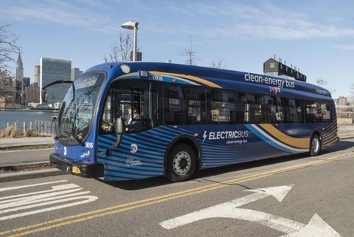 Electric Bus driving by river with cityscape in background