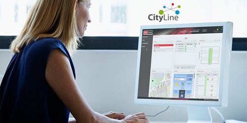 Blonde-haired business woman in blue blouse looks at a computer monitor