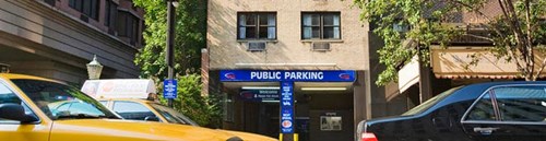 Yellow taxis drive past the entrance to a public parking facility