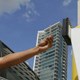 Person reaches from car window to use exit barrier at a car park, skyscraper in background