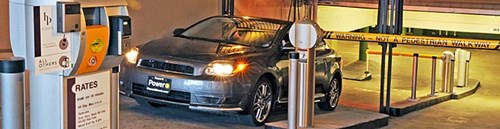 Car exits a parking facility, showing ticket machines and barrier