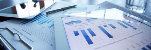 Selection of papers displaying graphs laid out on a desk with a pen and tablet