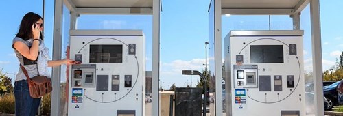 Two parking machines stand side by side and woman inserts card into the left machine