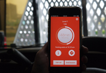 Person in car holds a smart phone display a screen with a red background and white circle display 48 minutes