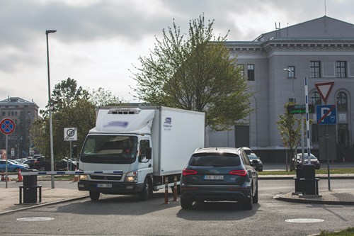 Two vehicles by the entrance and exit of the car park, waiting for the barrier to open