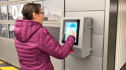 Woman in pink coat uses screen at a parking facility