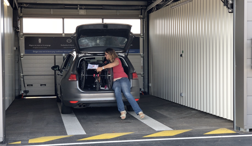 Woman unloads wheelchair from car boot whilst inside parking garage