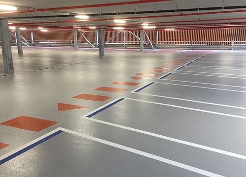 Interior of empty parking garage showing red walkway for pedestrians and pink family space