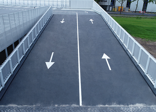 Ramps of a parking garage, newly surfaced in black and painted with white directional arrows