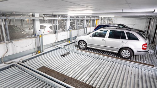 Parking lift in a parking garage, two empty spaces then a silver, blue and black car